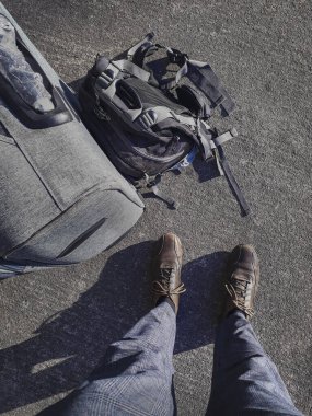 Üst görüşlü adam, bavul ve sırt çantalarını aspalth üzerinde görüyor.