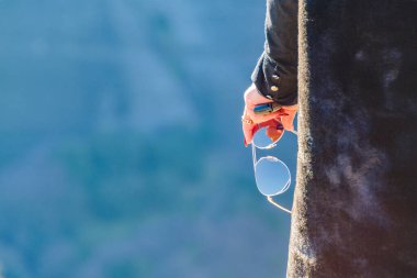 Arka plan zoom kadını elinde güneş gözlüğü resmi tutuyor.