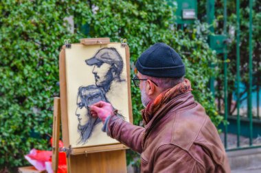 PARIS, FRANCE, JANUARY - 2020 - Old man painter drawing portraits at montmartre street.