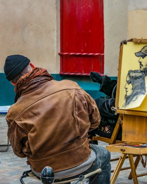 PARIS, FRANCE, JANUARY - 2020 - Painter watching portrait drawing at montmartre street.