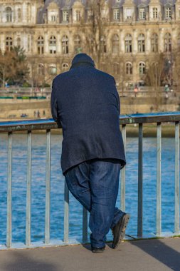 Arkaya bakan yetişkin şişman adam Briç, Paris, Fransa 'da nehri izliyor.