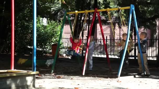 Crianças montando em um balanço . — Vídeo de Stock