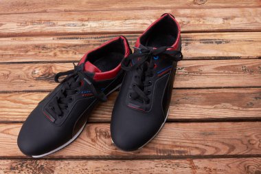 Ahşap arka planda izole siyah spor ayakkabılar.