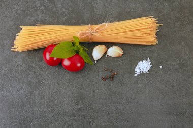 fesleğenli siyah bir arka planda spagetti.