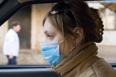 Young woman travels on automobile in a protective mask