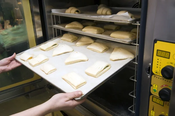 Pães doces sendo carregados em um forno Imagens De Bancos De Imagens