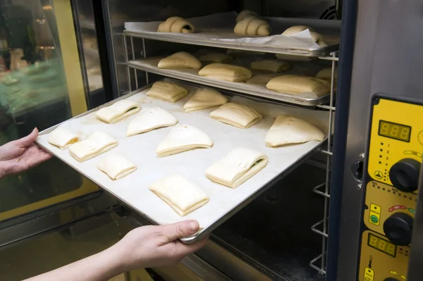 Süße Brötchen werden in den Ofen verladen Stockbild