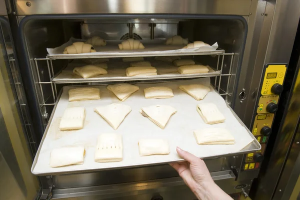 Pães doces sendo carregados em um forno Imagens De Bancos De Imagens