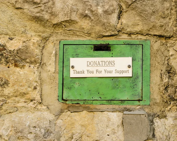 Vecchia scatola di donazioni verdi incastonata nel muro di pietra . Foto Stock