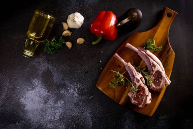 Çiğ kuzu kaburgaları baharat ve kavrulmuş sebzelerle tahta kesiyor.