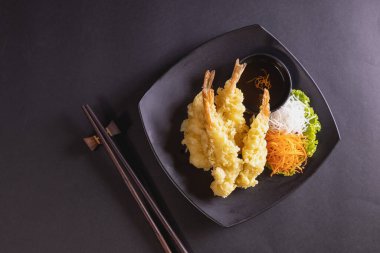 Sebzeli ve soslu siyah tabakta karides tempura.