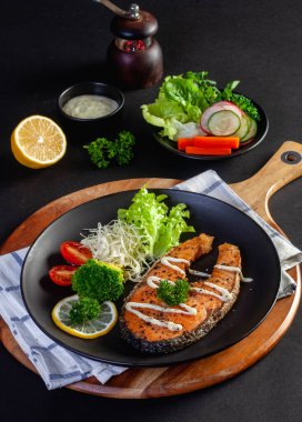 Siyah arka planda siyah tabakta somon bifteği.