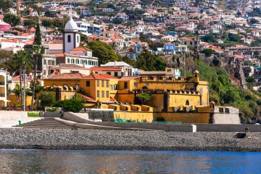 Madeira adası. Sao Tiago Kalesi ve şehir plajı için deniz kenarından Funchal kasabası manzarası. Portekiz seyahati ve simgeleri