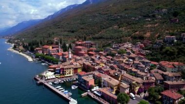 Scenic Lake Lago di Garda, Italy, aerial drone video of fishing village with colorful houses and boats - Castelletto di Brenzone