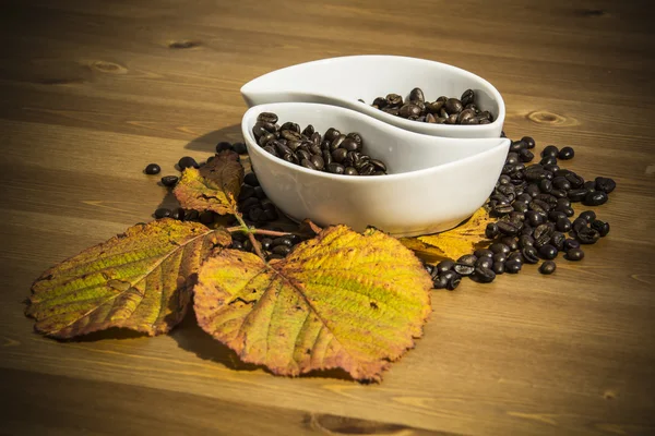 Tazze con chicchi di caffè su un tavolo di legno — Foto Stock