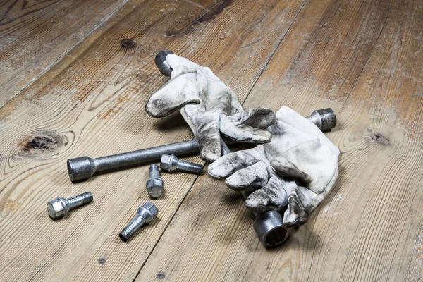 Old used wrench with screw and dirty gloves — Stock Photo, Image