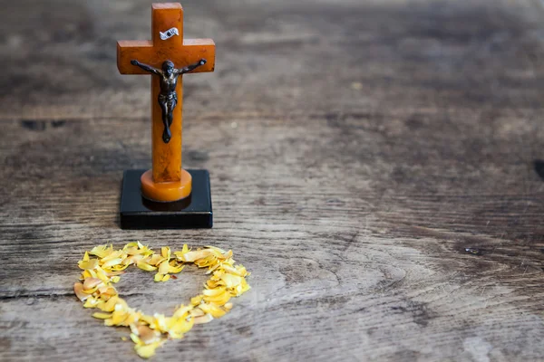 Bela cruz velha com Jesus e coração de folhas no chão de madeira velha — Fotografia de Stock
