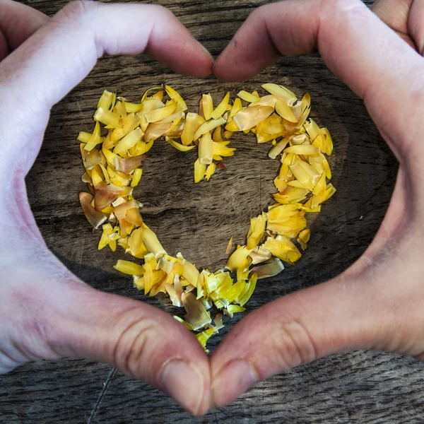 Un cuore da petali che si trovano su un tavolo di legno e mani — Foto Stock
