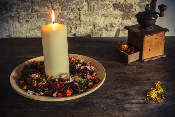 Свеча на деревянной тарелке с кофейной мельницей — стоковое фото