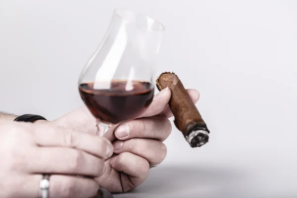 Vecchio brandy in vetro e sigaro in mano maschile su sfondo bianco — Foto Stock