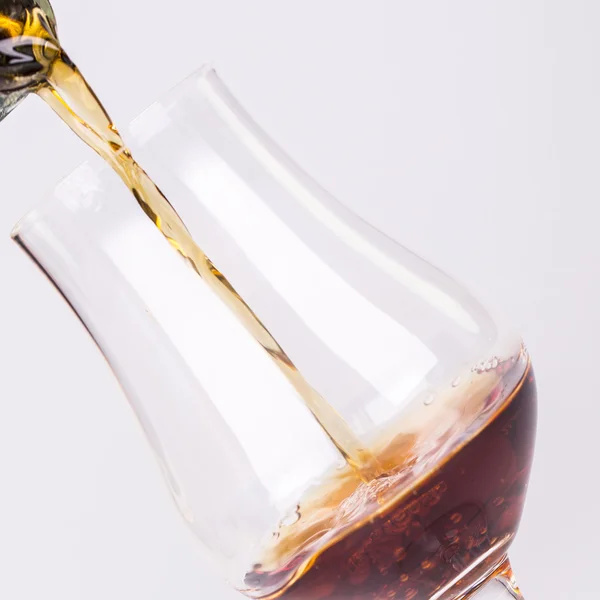 Bebida alcoólica derramando em vidro isolado em fundo branco — Fotografia de Stock