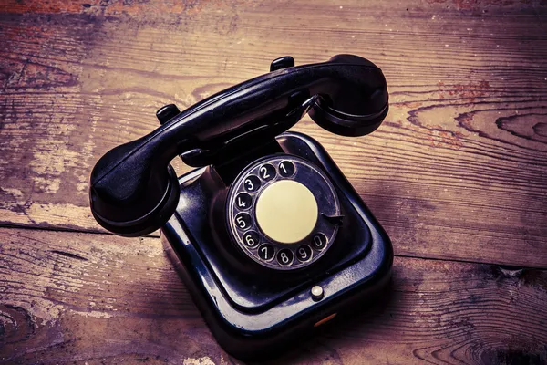 Vecchio telefono nero con polvere e graffi sul pavimento in legno — Foto Stock