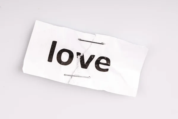 "Love" word written on torn and stapled paper — Stock Photo, Image