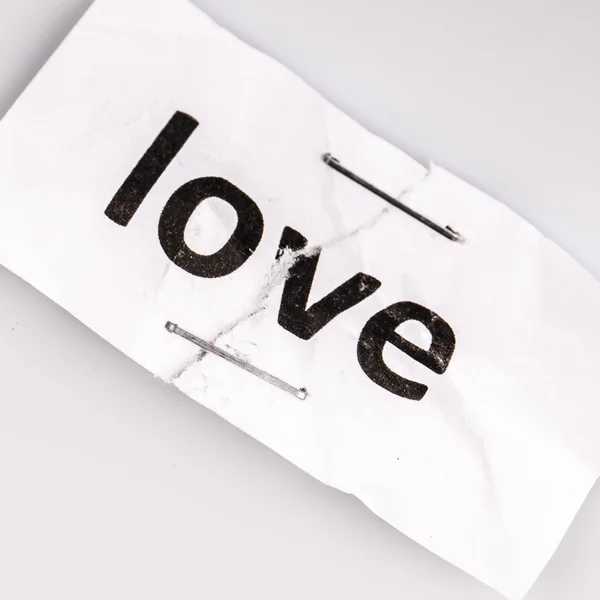 "Love" word written on torn and stapled paper — Stock Photo, Image