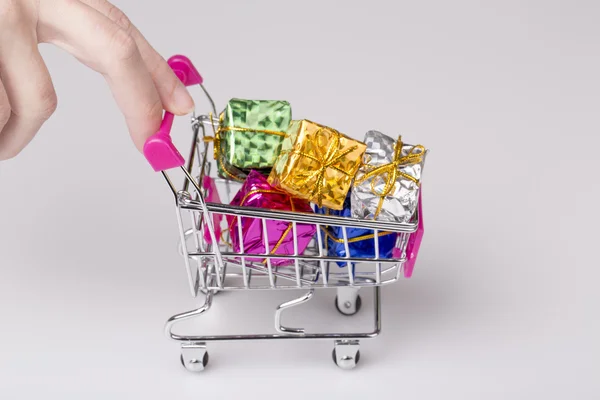 Pink shopping cart in woman hand and blue gift — Stock Photo, Image