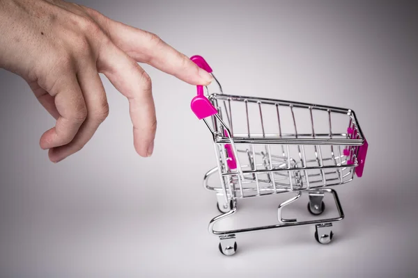 Carrinho de compras rosa na mão da mulher — Fotografia de Stock