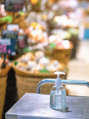 Corona virüsünün (Covid-19) süpermarketten almadan önce müşteriler için giriş servisinde yayılmasını önlemek için el temizliği için alkol jeli şişelerini temizleyin. Yeni normal yaşam tarzı.