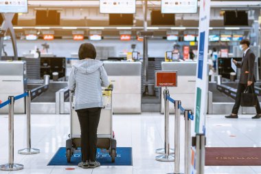 Corona virüsünü (Covid-19) önlemek için havaalanında personel maskesi takan yolcuların arka görüntüsü yüz maskesi takılır. Covid-19 salgınından sonra yeni normal seyahat kavramı.