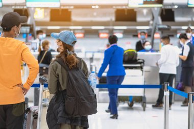Corona virüsünü (Covid-19) önlemek için havaalanında personel maskesi takan yolcuların arka görüntüsü yüz maskesi takılır. Covid-19 salgınından sonra yeni normal seyahat kavramı.