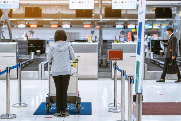 Corona virüsünü (Covid-19) önlemek için havaalanında personel maskesi takan yolcuların arka görüntüsü yüz maskesi takılır. Covid-19 salgınından sonra yeni normal seyahat kavramı.