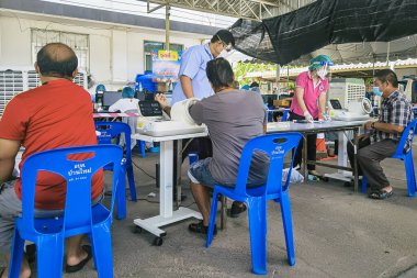 KANCHANABURI, THAILAND-AĞUSTOS 25. 2021: Kimliği belirsiz kişiler Tayland 'ın aşı süreci boyunca tüm yetişkinlere ilk doz COVILO (Sinopharm) Coronavirus aşısı için kuyrukta bekliyorlar.