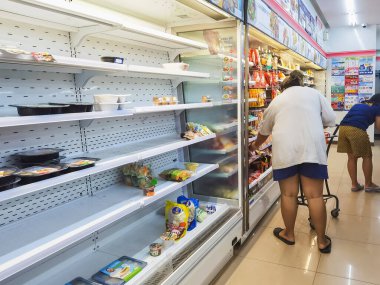 KANCHANABURI, THAILAND-AĞUSTOS 11,2021: Koronavirüs (COVID-19) yayılırken, tanımlanamayan kadın raflardaki yiyecekleri çoğunlukla boş olarak seçiyor..