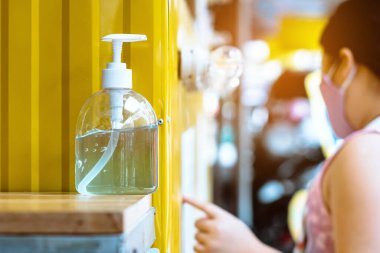 Corona virüsünün (Covid-19) yayılmasını önlemek için el temizliği için mavi alkol jeli şişesi, kafenin önündeki müşteriler için masa servisi. Yeni normal yaşam tarzı..