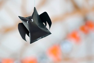 Origami sopası, Cadılar Bayramı süslemeleri için ipte asılı duran siyah kağıttan yapılmış. Karanlık kağıt hayalet Cadılar Bayramı parti konsepti origami kağıt yarasa. Odanın üzerinde uçan siyah kağıt yarasa figürü. Metin için boşluk.