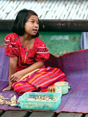KANCHANABURI THAILAND-Aralık 31,2019: Kimliği belirlenemeyen Mon kızı çiçek satıyor ve Sangkhlaburi 'deki nehrin karşısındaki Uttamanusorn ahşap köprüsünde turistlere pudra hizmeti veriyor..