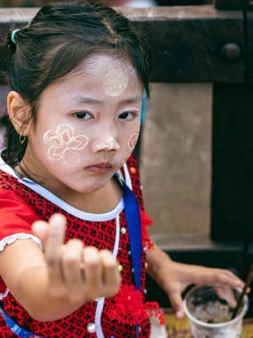 KANCHANABURI THAILAND-Aralık 31,2019: Kimliği belirlenemeyen Mon kızı çiçek satıyor ve Sangkhlaburi 'deki nehrin karşısındaki Uttamanusorn ahşap köprüsünde turistlere pudra hizmeti veriyor..