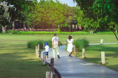 KANCHANABURI, THAILAND-FEBRUARY 20.2021: Tanımlanamayan Asyalı neşeli bir ailenin yeşil bahçede rahatlamak için köy çiftliğinden kafeteryaya yürüyüşü. Doğanın tadını çıkarıyorum