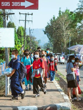 KANCHANABURI, THAILAND-JANUARY 14. 2022: Okuldan eve dönerken Corona virüsünü (COVID-19) önlemek için beş farklı milletten (Tayland, Lao, Mon, Karen ve Birmanya) öğrenciler maske takıyor.
