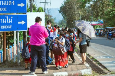 KANCHANABURI, THAILAND-JANUARY 14. 2022: Okuldan eve dönerken Corona virüsünü (COVID-19) önlemek için beş farklı milletten (Tayland, Lao, Mon, Karen ve Birmanya) öğrenciler maske takıyor.