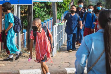 KANCHANABURI, THAILAND-JANUARY 14. 2022: Okuldan eve dönerken Corona virüsünü (COVID-19) önlemek için beş farklı milletten (Tayland, Lao, Mon, Karen ve Birmanya) öğrenciler maske takıyor.