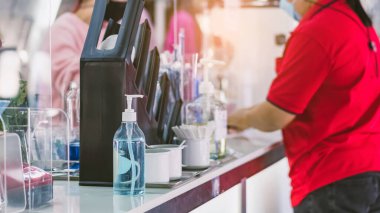 Coronavirus 'un (Covid-19) kahve ya da kahve dükkanındaki müşterilerin hizmetine sunulmasını önlemek için el temizliği için mavi alkol jeli şişesi. Sağlık sigortası konsepti. Yeni normal yaşam tarzı.