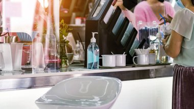 Coronavirus 'un (Covid-19) kahve ya da kahve dükkanındaki müşterilerin hizmetine sunulmasını önlemek için el temizliği için mavi alkol jeli şişesi. Sağlık sigortası konsepti. Yeni normal yaşam tarzı.