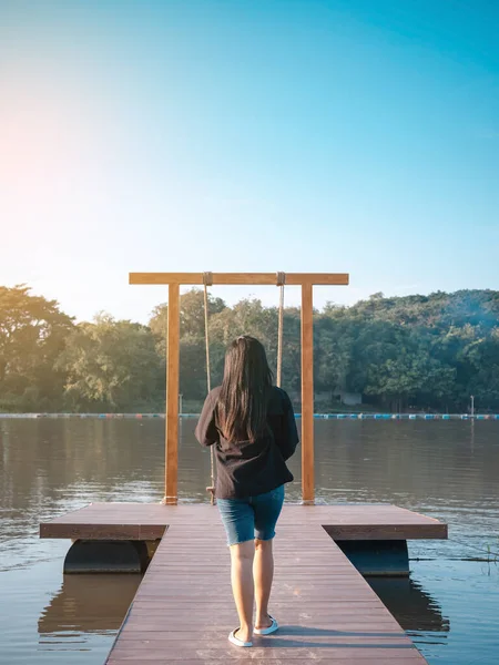 Genç Asyalı bir kadının yaz tatilinde nehir kıyısında tahta bir bankta salıncakta sallanmak için yürüdüğünü görmek. Rıhtımda yapayalnız bir kız ve akşam vakti güzel büyük bir nehirde doğa manzarasının tadını çıkarıyor..