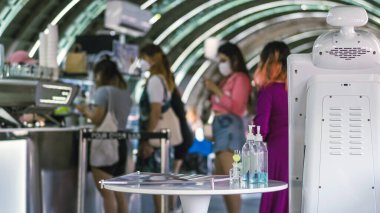 Coronavirus 'un (Covid-19) kahve ya da kahve dükkanındaki müşterilere servis edilmesini önlemek için el temizliği için mavi alkol jeli şişesi. Sağlık sigortası konsepti. Yeni normal yaşam tarzı.