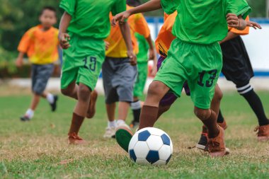 Football soccer children training class. Kindergarten school kids playing football in a field. Group of boys running and kicking soccer on sports grass pitch. Children in sportswear on football match.