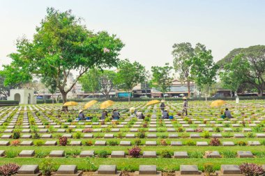 KANCHANABURI THAILAND - 21 Şubat: Kimliği belirsiz işçiler, 21 Şubat 2020 'de Kanchanaburi, Tayland' daki Kanchanaburi Müttefik Savaş Mezarlığı 'nda çiçek yenileyip dekore ediyorlar